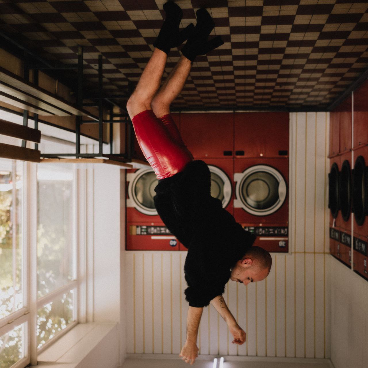 An upside-down picture of a young person standing inside a laundromat